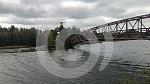 Suspension bridge leading to the Church of St. Andrew on the island. Vuoksa river in the season of white nights.