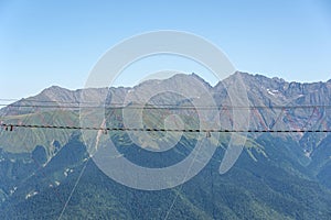 Suspension bridge in the mountains over the abyss. Away against the backdrop of the peaks of the mountain ranges