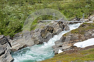 Suspension Bridge in the Mountains over fast flowing turbulent river