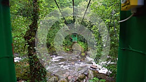 Suspension bridge in the mountains over a stormy tropical river.