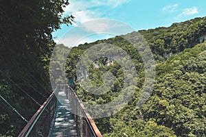 Suspension bridge in Okatse Canyon, village Gordi, Imereti region, Georgia. Narrow path surrounded by hills covered by