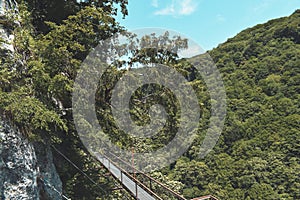 Suspension bridge in Okatse Canyon, village Gordi, Imereti region, Georgia. Narrow path surrounded by hills covered by