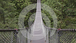 Suspension bridge over the canyon and waterfall with forest and trees in Canadian Nature