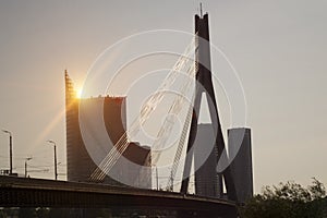 Suspension bridge over the Daugava River on a sunset on background of the modern part of the city. Latvia