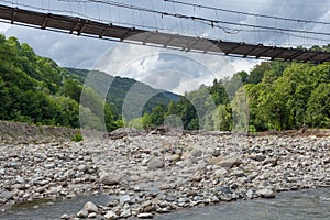 Suspension bridge over the mountain river