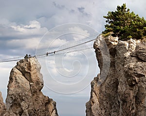 Suspension bridge between the rocks. Air mountain road, tourists. Photo.