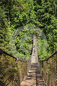 Suspension bridge with tourists walking on it in Lynn Canyon park in Vancouver