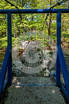 Suspension footbridge spans the river with waterfall.