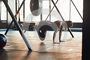 Suspension Training. Side view of young caucasian fitness woman in sportswear doing TRX workout at industrial gym