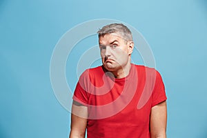 Suspiciont. Doubtful pensive man with thoughtful expression making choice against blue background