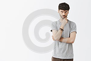 Suspicious adult man with beard frowning and staring with disbelief and doubt left, being unsure if he can trust seller