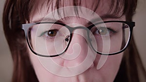 Suspicious brunette woman with glasses looking at the camera close-up