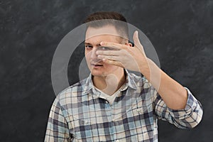 Suspicious man peeking through fingers