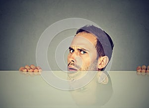 Suspicious man peeking from under table