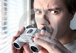 Suspicious, skeptic and confused man with binoculars. Conspiracy theory, paranoia, skepticism or suspicion concept. photo