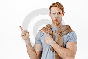 Suspicious, skeptical redhead man having doubts and asking question about item, pointing at upper left corner something