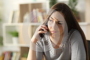 Suspicious woman calling on phone sitting at home photo