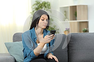 Suspicious woman checking phone content at home photo