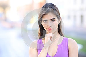 Suspicious woman looking at camera standing in the street