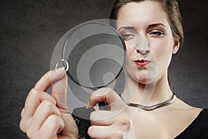 Suspicious woman looking at her wedding ring through magnifying glass