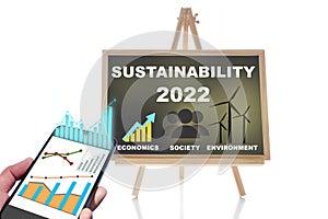 2022 sustainability on chalkboard and online financial technology or fintech on smartphone on white background