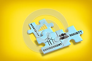 Environment society and economics written on blue puzzle jigsaw with shadow on yellow background photo