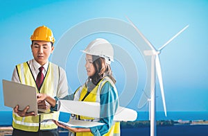Sustainable Energy engineer male and female is discussing on document plant with Wind turbine