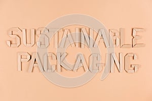 Sustainable paper packaging concept. Text Sustainable Packaging over light brown background