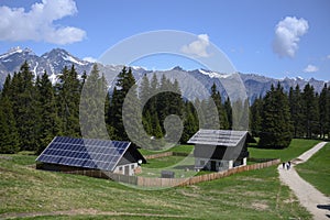 Sustainable photovoltaics houses in mountain alps at forest photo