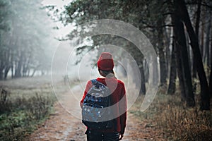 Sustainable tourism, responsible travel. Young woman traveler with backpack in pine forest background.