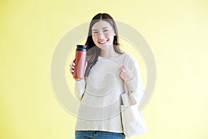 Sustainable and zero waste concept, Young asian woman smiling and holding reusable bottle looking at camera while standing on