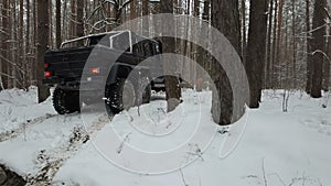 SUV 6x6 standing on a snow-covered road in winter forest, back view