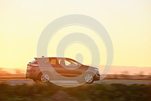 SUV car driving fast on intercity road at sunset. Highway traffic in evening