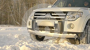 Suv car driving on snowdrift at winter road on snowy forest background slow motion