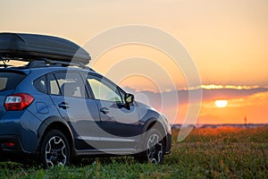 SUV car with roof rack luggage container for off road travelling parked at roadside at sunset. Road trip and getaway concept photo