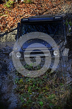 SUV covered with mud stuck in puddle.