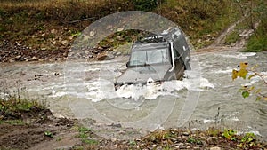 The SUV is crossing a rough river. Water is above the wheels