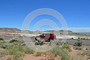 SUV driving on Rpad thru Petrified National Forest Sandy Desert Crusty Surface Road