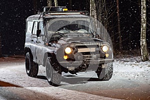 The suv is driving on a snowy night road photo