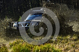 SUV or offroad car on path covered with grass crossing puddle with dirt splash. Extreme, challenge and 4x4 vehicle