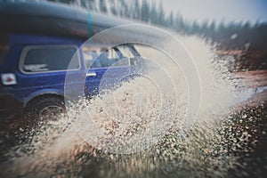 Suv offroad 4wd car rides through muddy puddle, off-road track road, with a big splash, during a jeeping competition