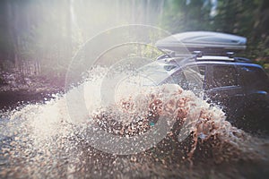 Suv offroad 4wd car rides through muddy puddle, off-road track road, with a big splash, during a jeeping competition