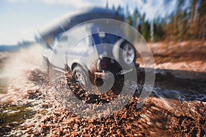 Suv offroad 4wd car rides through muddy puddle, off-road track road, with a big splash, during a jeeping competition