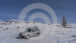 The SUV is parked on a snowy valley.