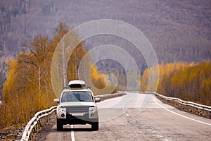 SUV on scenic autumn road in the forest