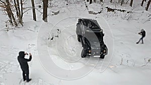 SUV to ride out of a deep pit in the snow-covered road in winter forest. Off-road