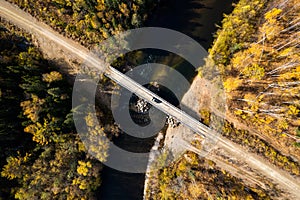 SUV on wooden bridge over small mountain river. Autumn forest