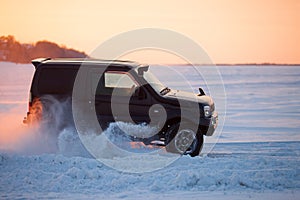 Suzuki Jimny moving on ice of a frosen river at sunset photo