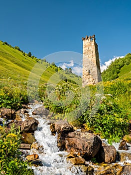 Svan tower by river in Adishi village, Caucasus mountains, Mestia district, Georgia photo