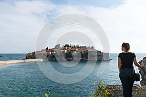Sveti Stefan in Budva Montenegro Young girl traveler. Adriatic sea with boats and an old small town in a island. Stone luxury
